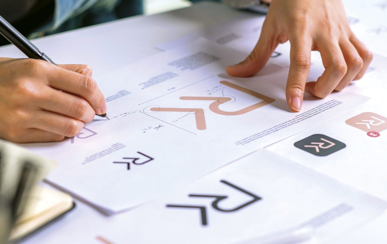 Personne dessinant des logos sur papier.